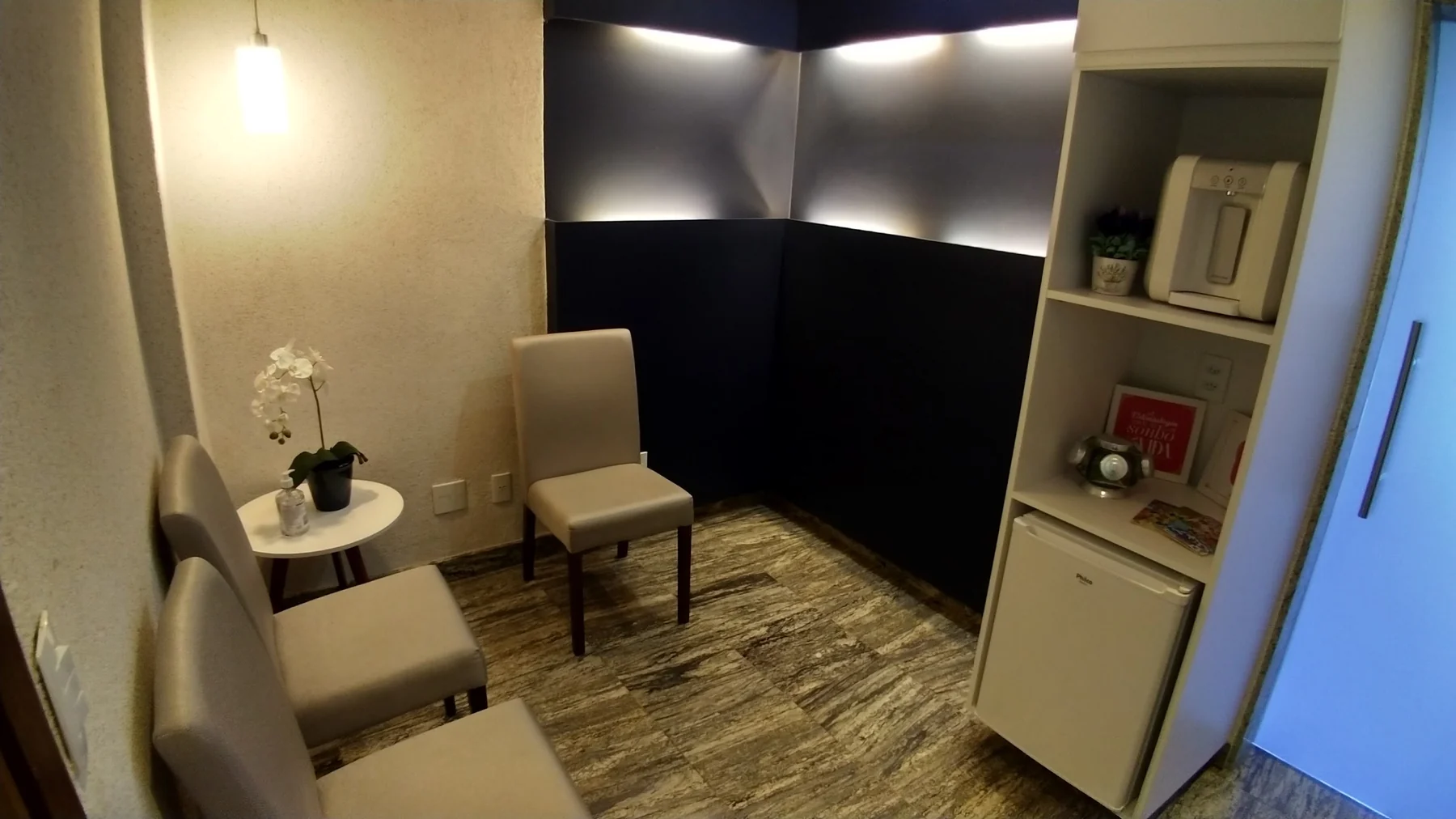 Sala de espera da CORP, com poltronas, orquídea e iluminação indireta